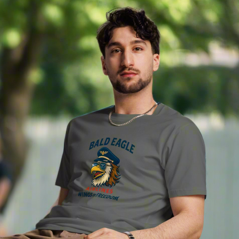 Man sitting on a chair outdoors wearing a gray t-shirt with a graphic design.