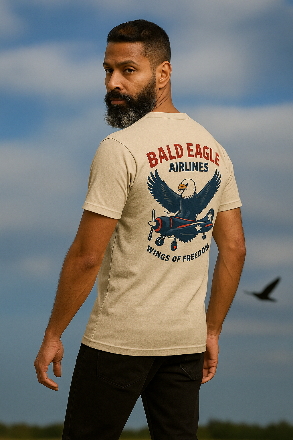 Man wearing a t-shirt with 'Bald Eagle Airlines' design against a cloudy sky.