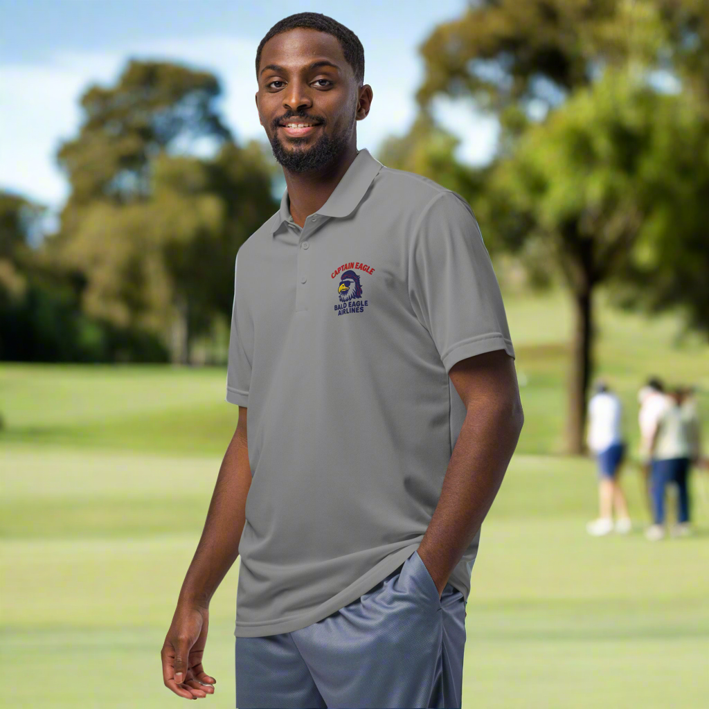 Man wearing a gray polo shirt with a logo on a golf course